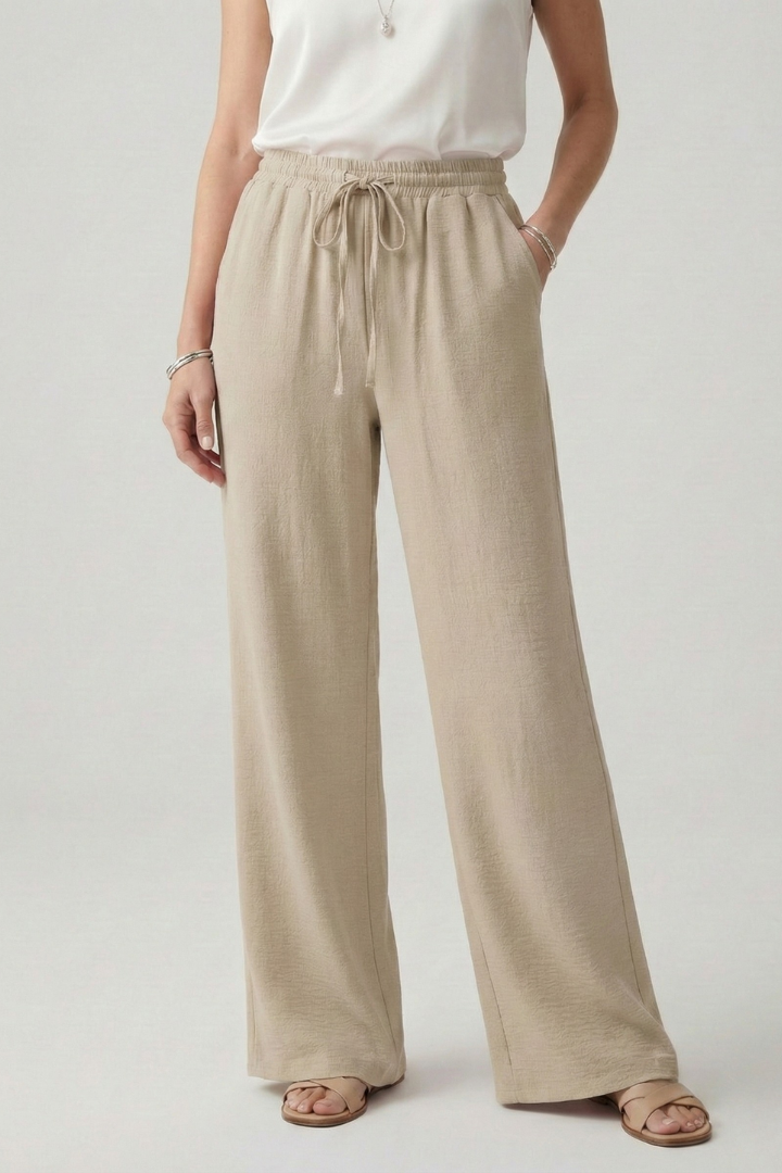 Detail of women's palazzo trousers: drawstring waist, side pockets & flowing wide-leg design for casual comfort.