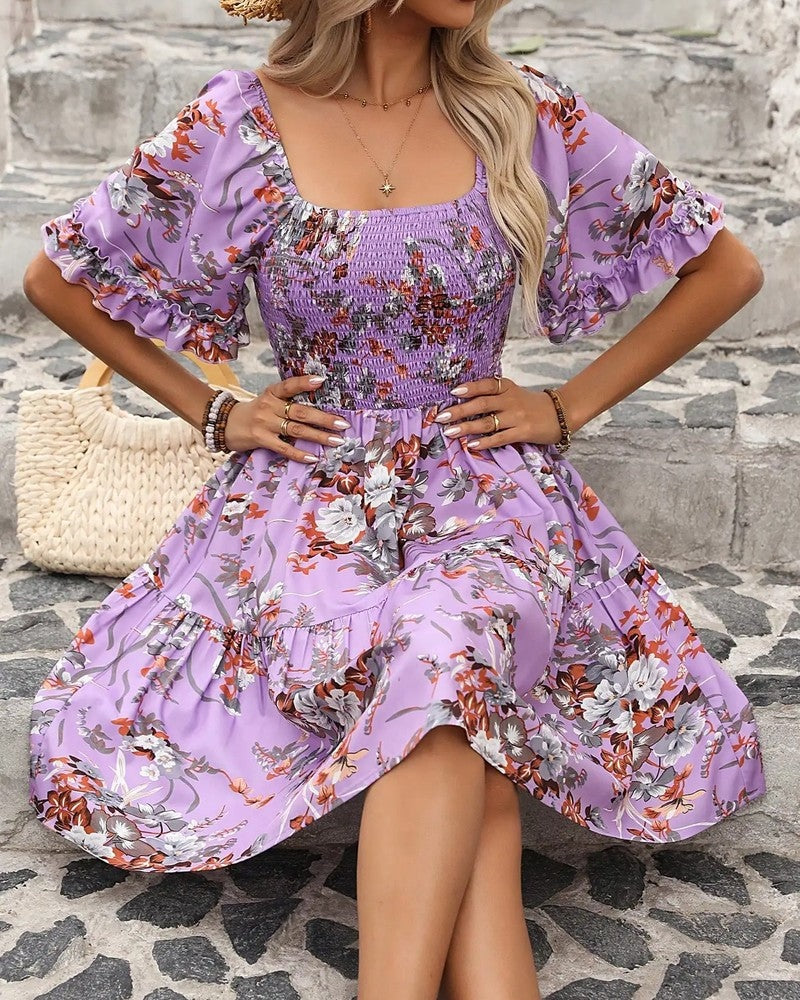 Close-up of a women's floral smocked mini dress. Details include puff sleeves and a lively flower pattern.