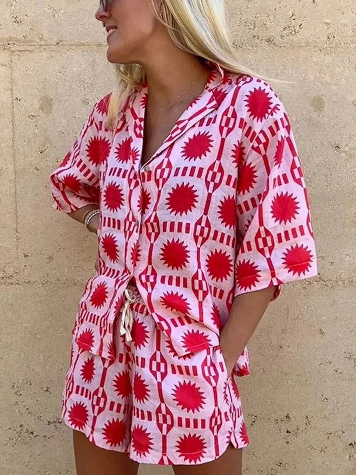 Stylish women's pink geometric print two-piece set with short-sleeved shirt & matching shorts, ideal for vacation wear.