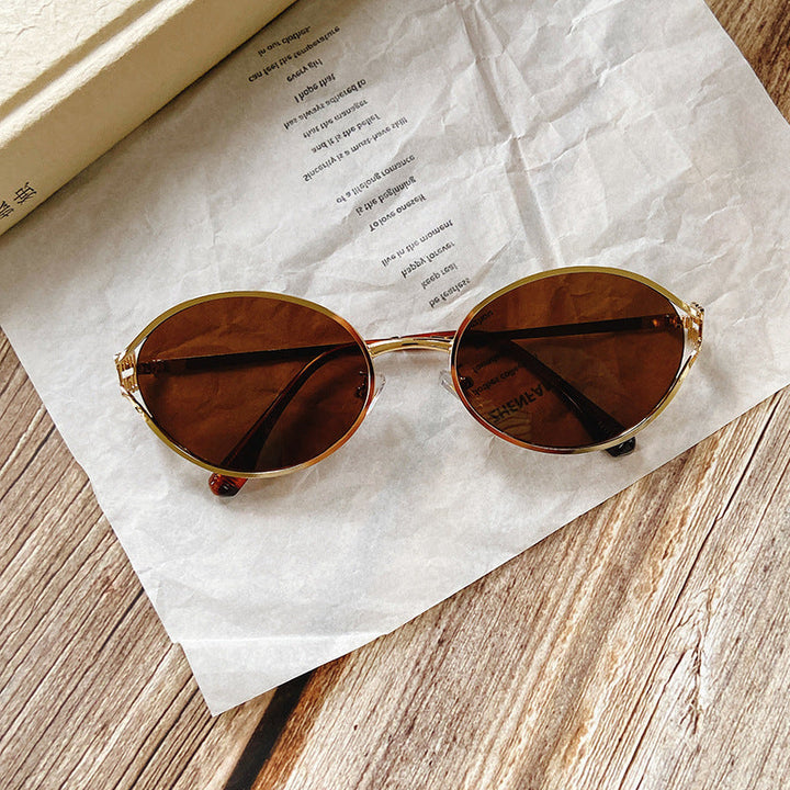 A pair of women's round sunglasses, combining eye protection with chic gold-toned accents.