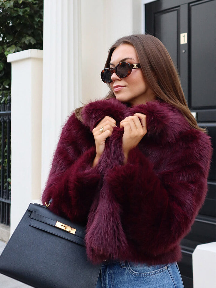 Front view of a women's classic faux fur coat with a prominent wide lapel collar. Elegant & warm winter jacket.