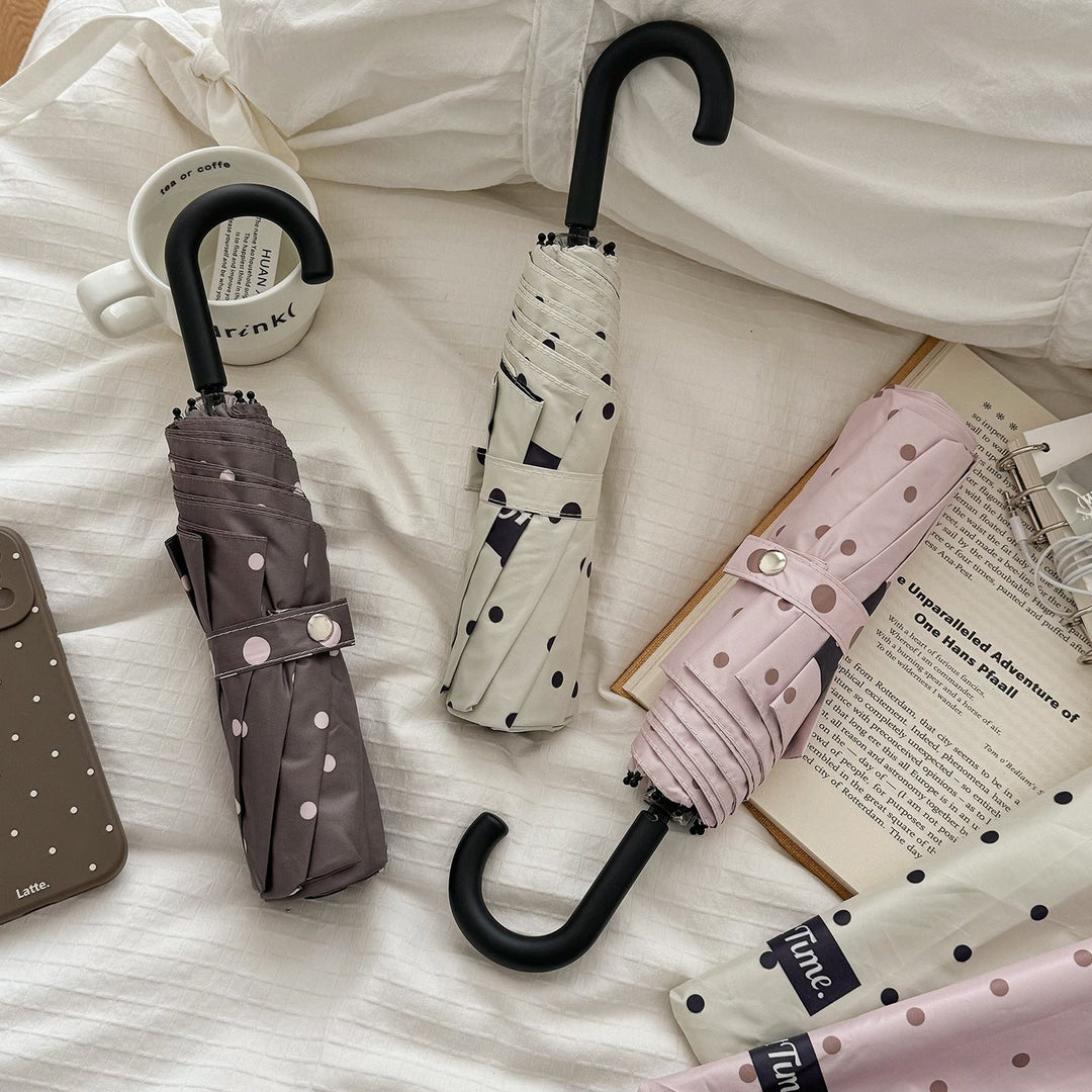 Women's compact polka dot folding umbrella, portable weather protection for rain & sun.