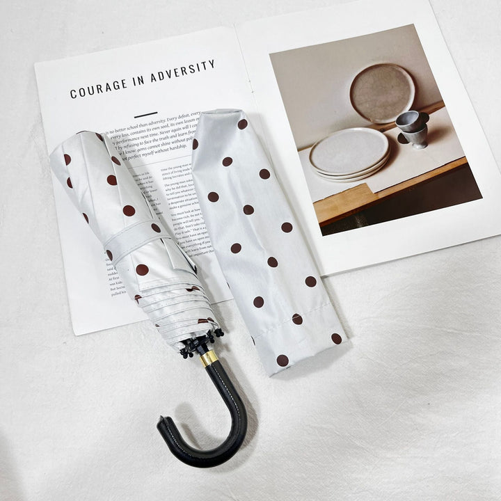 Compact women's folding umbrella, stylish polka dot, essential for travel and everyday rain.