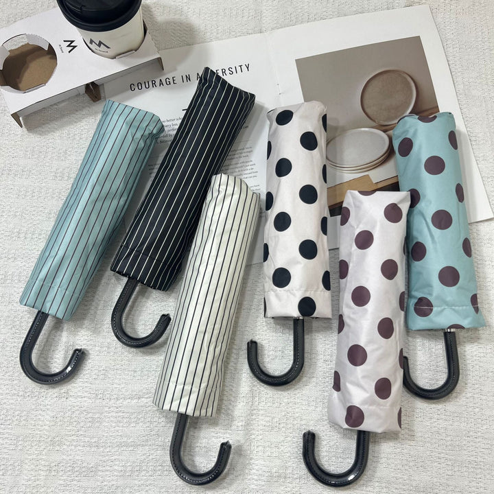 Stylish polka dot women's travel umbrella, compact & lightweight for all-weather defense.