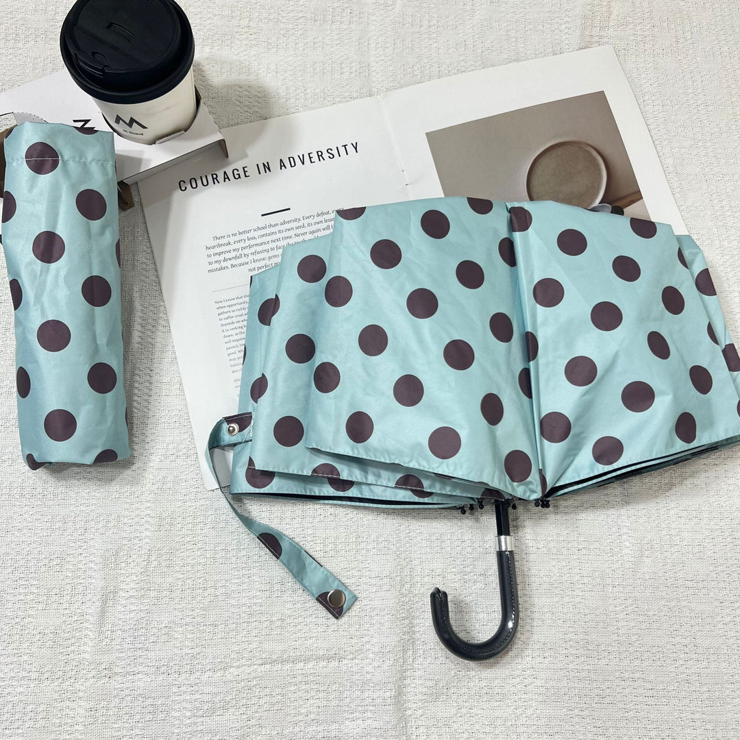 Compact & stylish women's folding umbrella, polka dot pattern for portable weather defense.