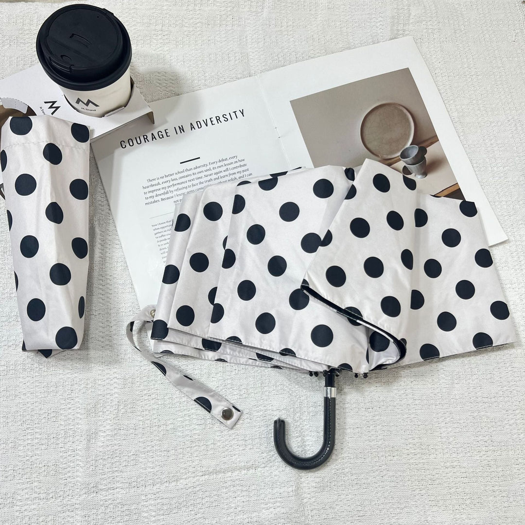 Women's compact travel umbrella, polka dot design, perfect for sudden changes in weather.
