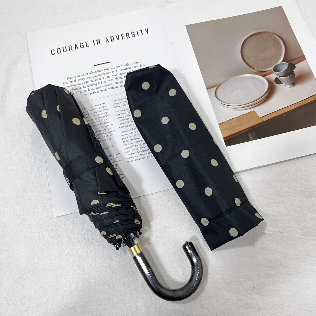 Stylish women's compact folding umbrella with polka dot pattern, easy travel companion.