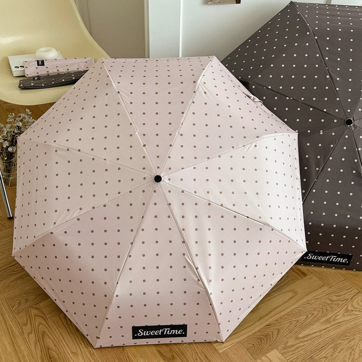 Women's travel-friendly umbrella, compact folding, chic polka dot for rain & UV protection.