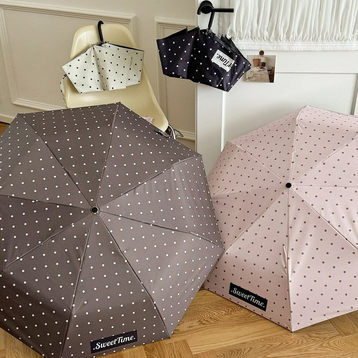Stylish women's compact umbrella, polka dot design, portable for versatile weather use.