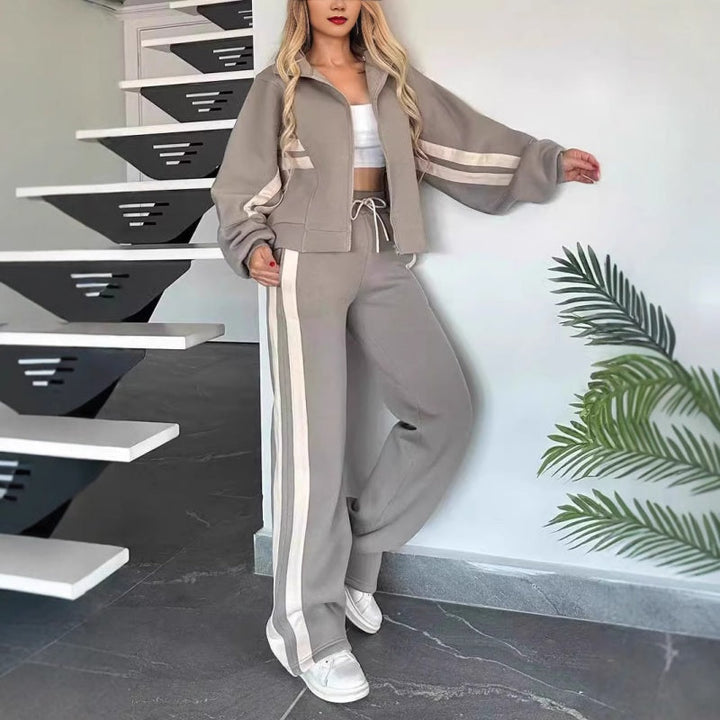 Two-piece women's lounge tracksuit. Zip-up top & wide-leg pants with stylish contrast stripes for comfort.