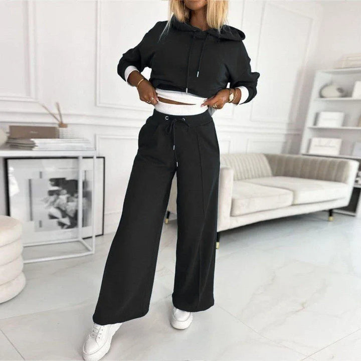 Woman relaxing in a comfortable knit hoodie and wide-leg pants lounge set, perfect winter fashion.