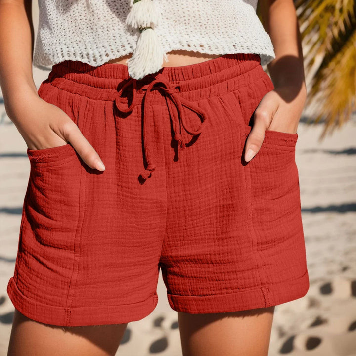 Model wearing women's crinkled drawstring waist shorts, cuffed hem, for stylish summer fashion.