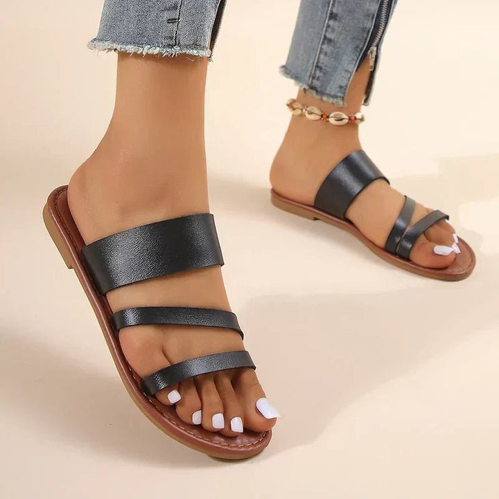 Flat women's sandals with soft cross-straps and a cushioned footbed, easy slip-on style for comfort.