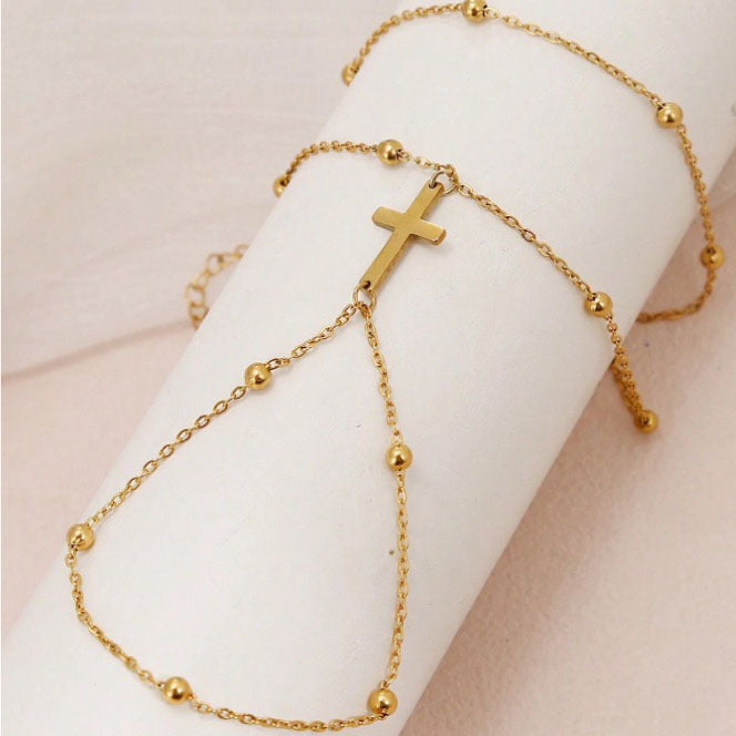 Close-up of a delicate gold cross charm on an adjustable women's bracelet, meaningful faith jewelry.