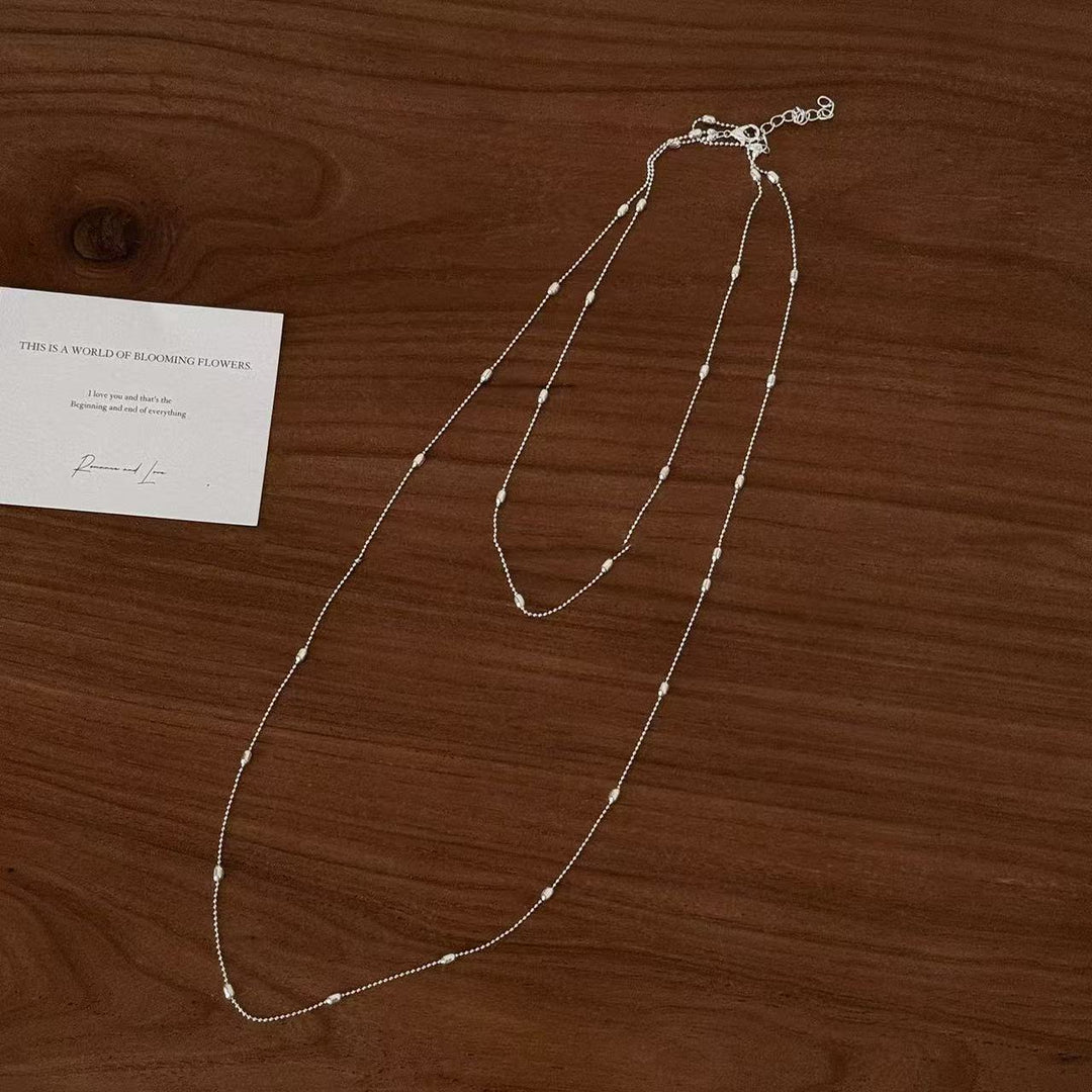 Close-up of a delicate layered silver chain necklace, showcasing its intricate design and fashion appeal.