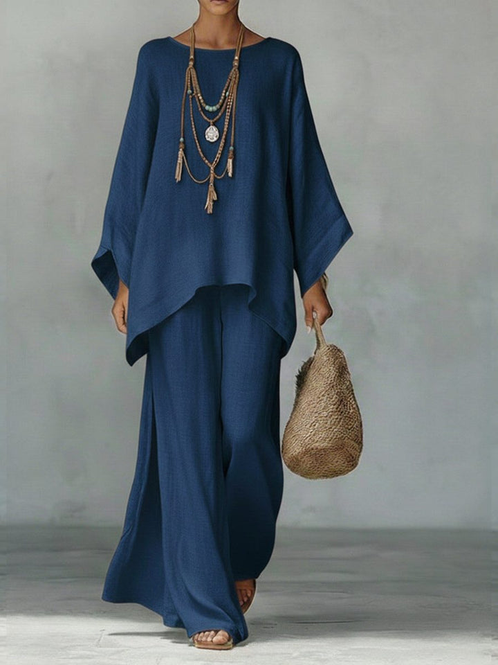 Woman wearing an effortless linen two-piece maxi set with poncho top & straight leg trousers, a chic summer outfit.