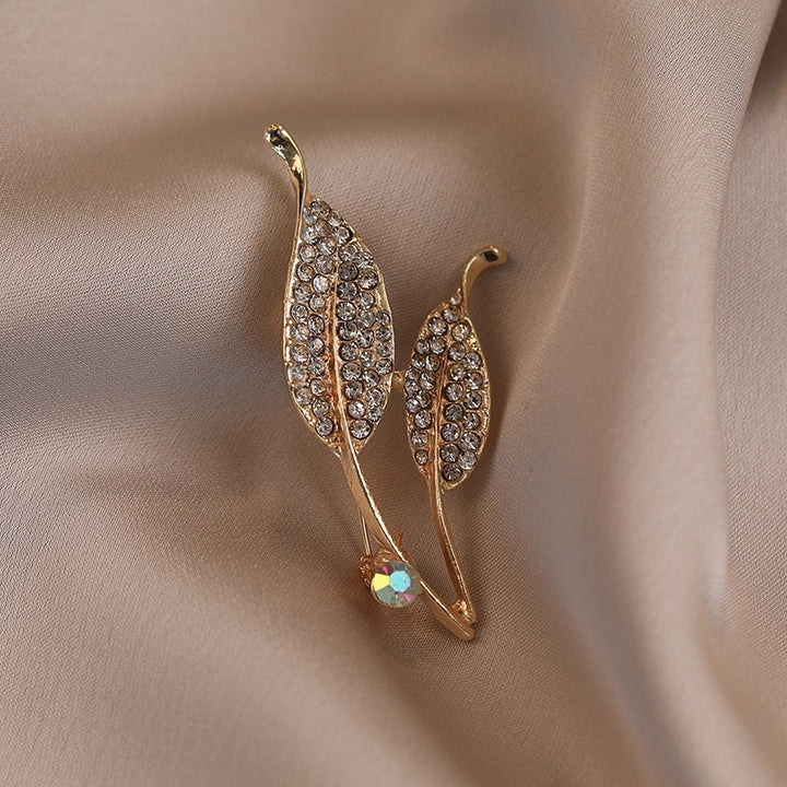 Women's elegant crystal leaf brooch pin with gold finish. Perfect for coats, dresses, and lapels.