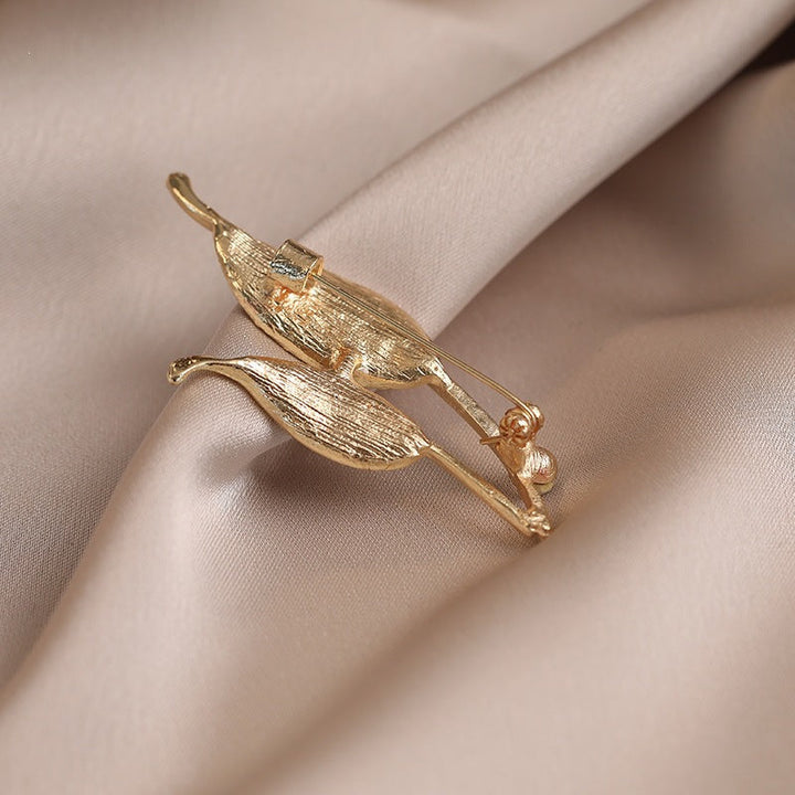 Gold-tone elegant leaf lapel pin adorned with shimmering crystals, enhancing any women's outfit.