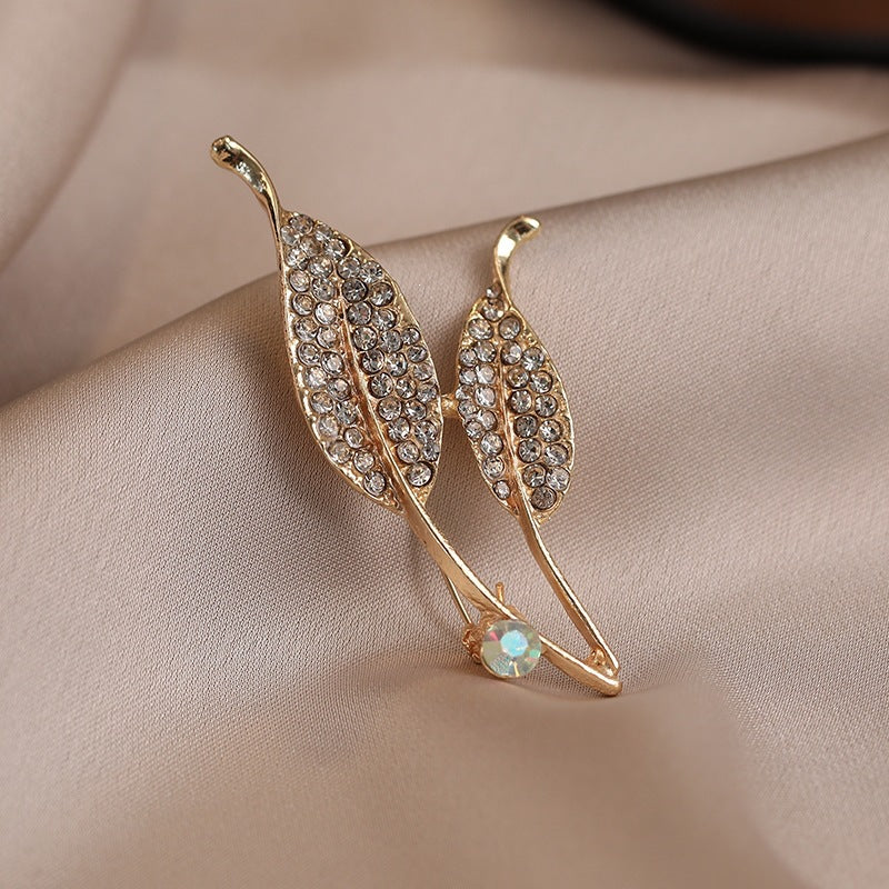 Beautiful gold finish women's brooch featuring an elegant crystal leaf design. A versatile fashion accessory.