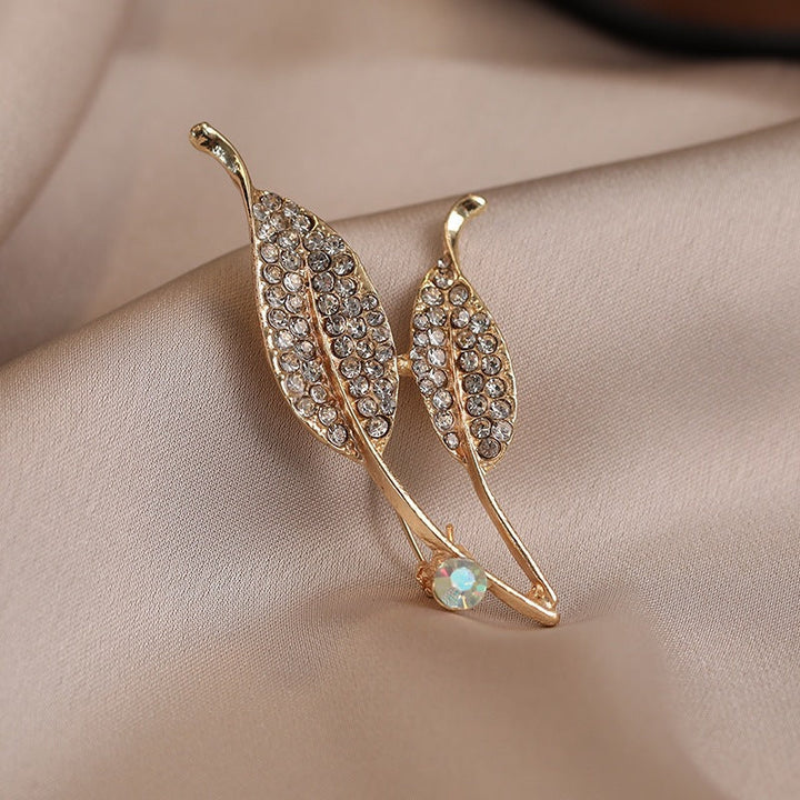 Beautiful gold finish women's brooch featuring an elegant crystal leaf design. A versatile fashion accessory.