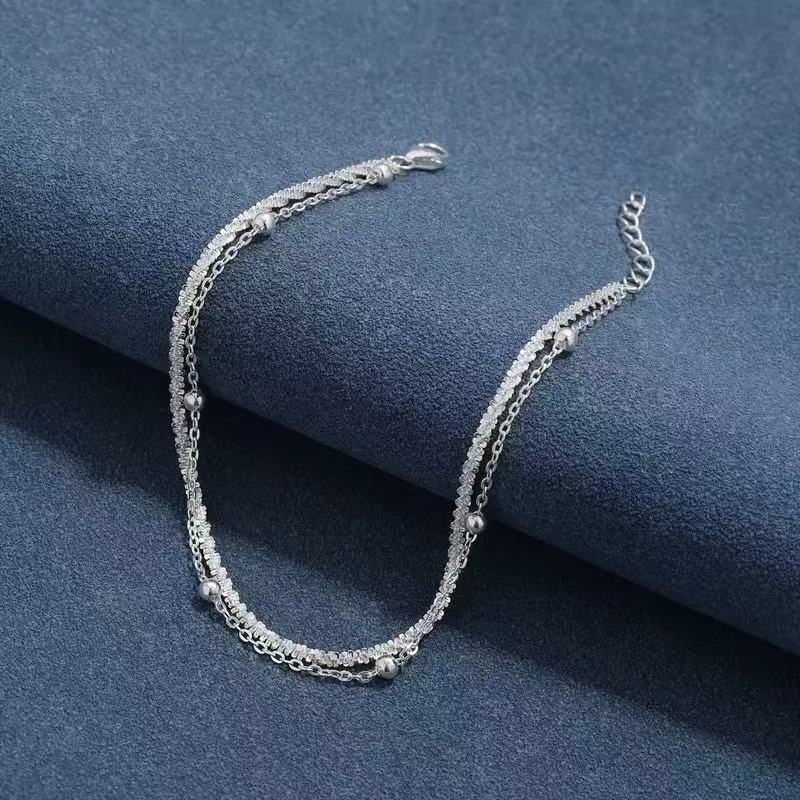 Close-up of a women's elegant dual-layer silver bracelet, showcasing minimalist style and delicate craftsmanship.