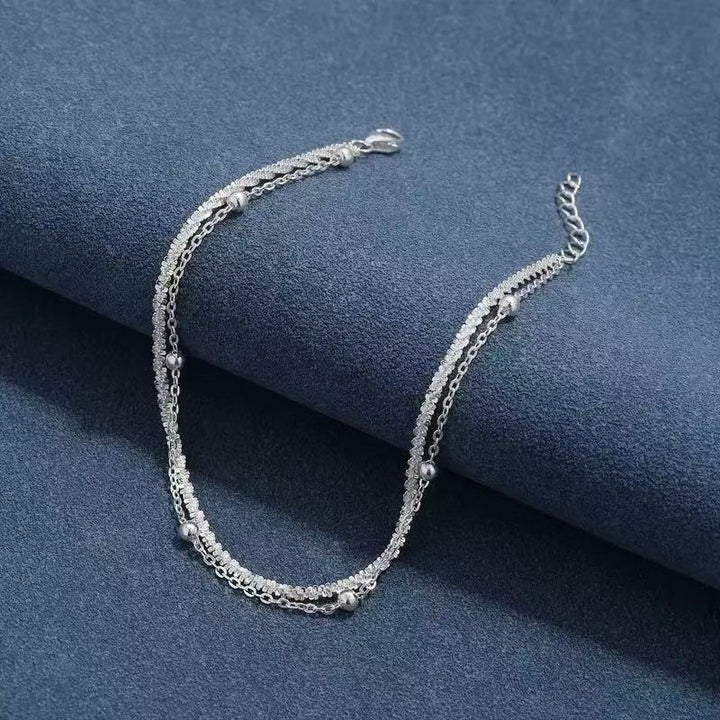 Close-up of a women's elegant dual-layer silver bracelet, showcasing minimalist style and delicate craftsmanship.