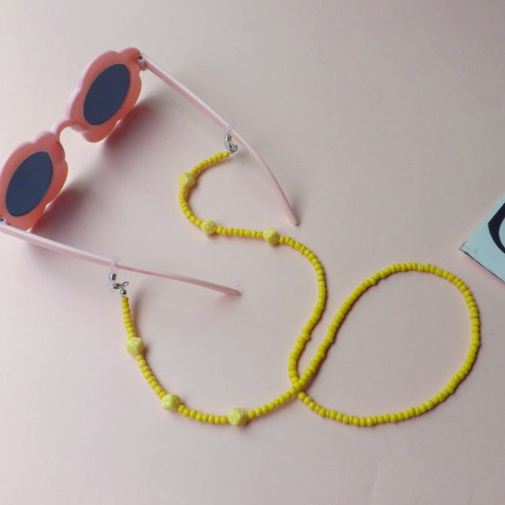 Stylish women's flower sunglasses with a delicate beaded strap, offering essential UV protection.