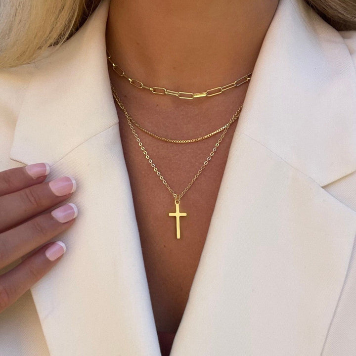 Women's elegant gold multi-layered necklace with a cross pendant. Fashionable spiritual jewelry.