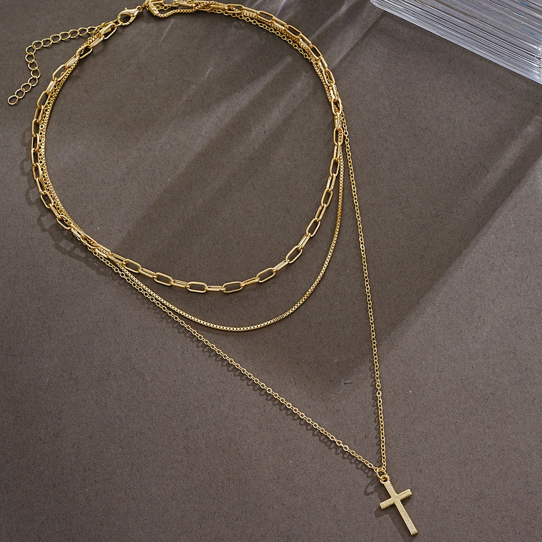 Gleaming gold cross pendant necklace for women, multi-layered design. Elegant and spiritual fashion accessory.