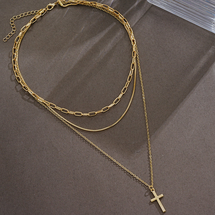 Gleaming gold cross pendant necklace for women, multi-layered design. Elegant and spiritual fashion accessory.