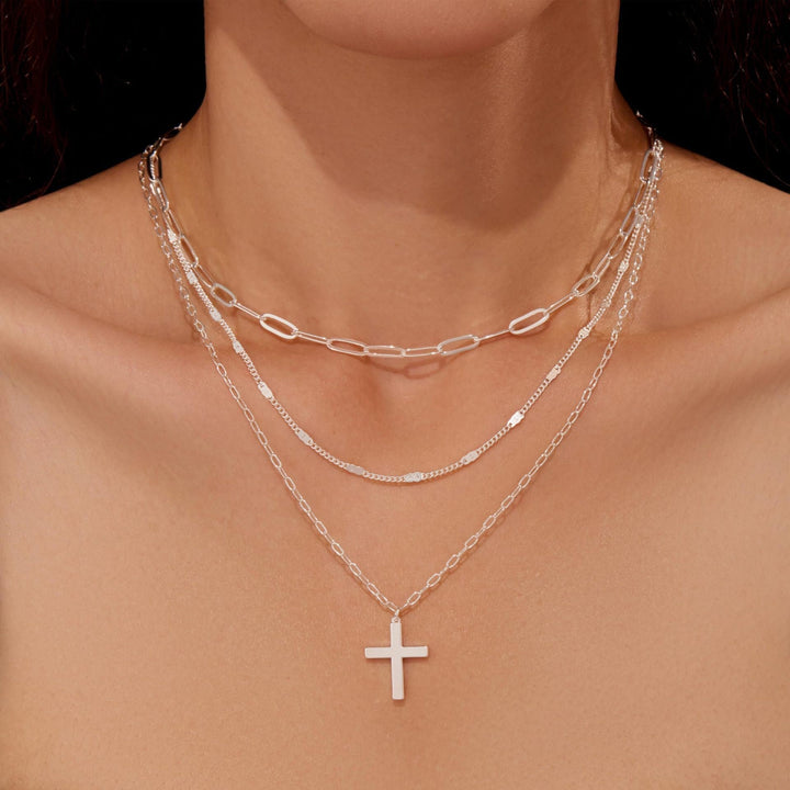 Delicate gold multi-layered necklace for women, adorned with a graceful cross pendant. Elegant spiritual accessory.