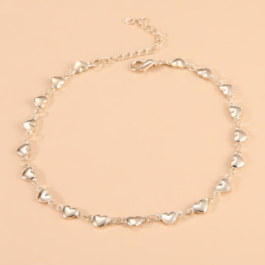 Close-up of elegant women's heart charm chain anklet, adjustable for perfect fit, chic summer jewelry.