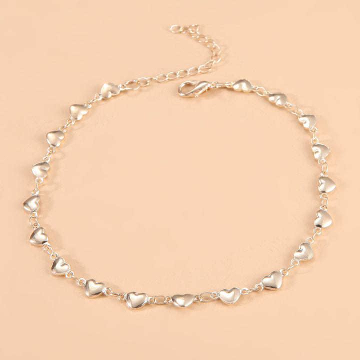 Close-up of elegant women's heart charm chain anklet, adjustable for perfect fit, chic summer jewelry.