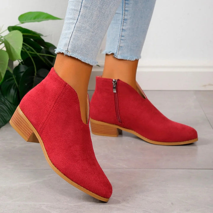 Detailed view of women's elegant pointed toe ankle boots with chic square heel and sleek finish.
