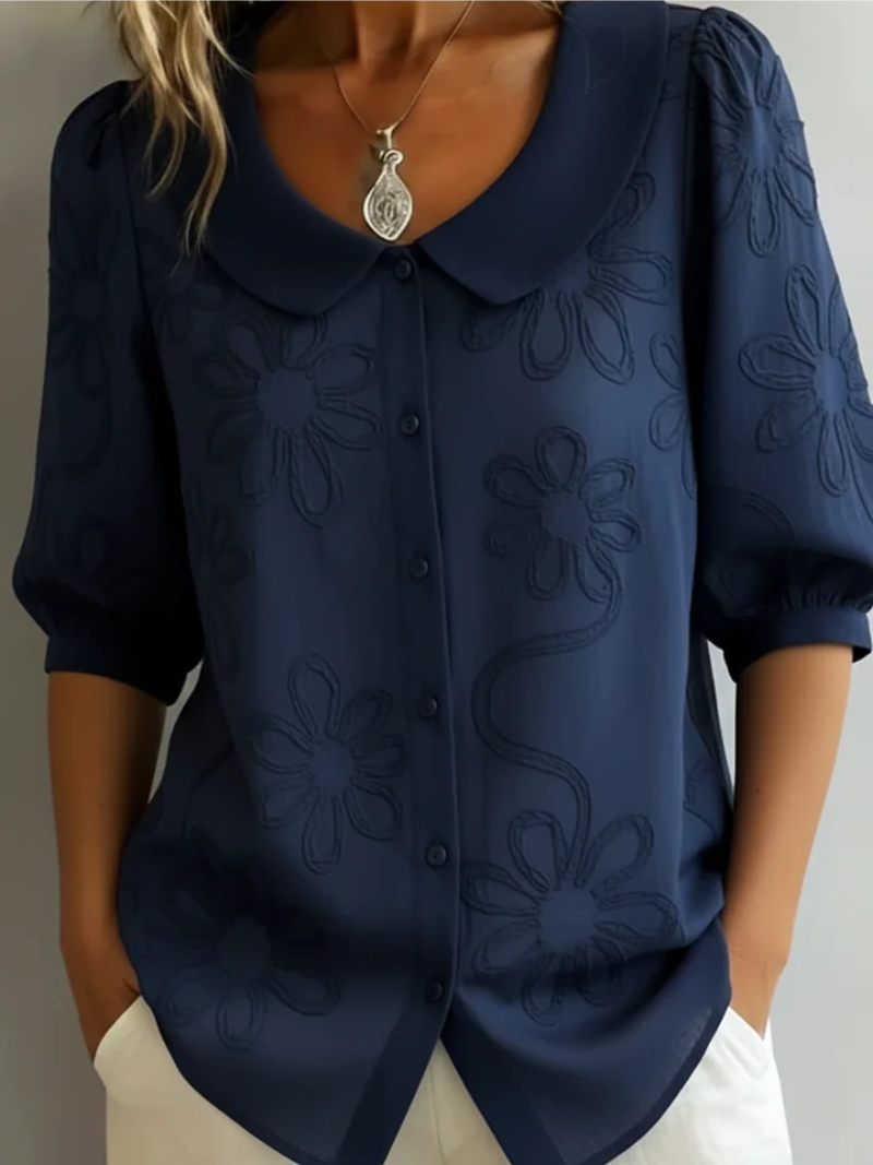 Elegant women's short sleeve blouse with delicate floral embroidery. Relaxed fit, round neck top perfect for spring fashion.