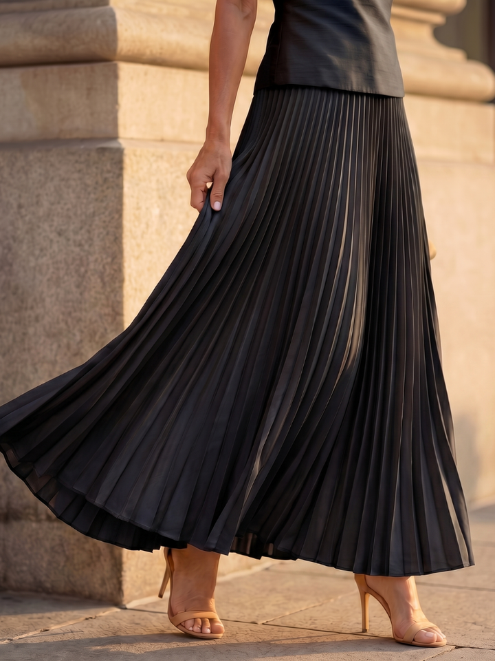Model in a chic women's structured bodice & elegant pleated skirt matching set, full view.
