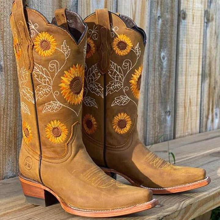 Close-up of women's mid-calf cowboy boots, showcasing detailed sunflower embroidery and quality craftsmanship.