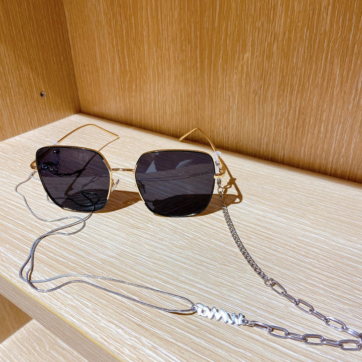 Women's fashion sunglasses with elegant chain strap, square frame, offering UV protection. Stylish eyewear for women.