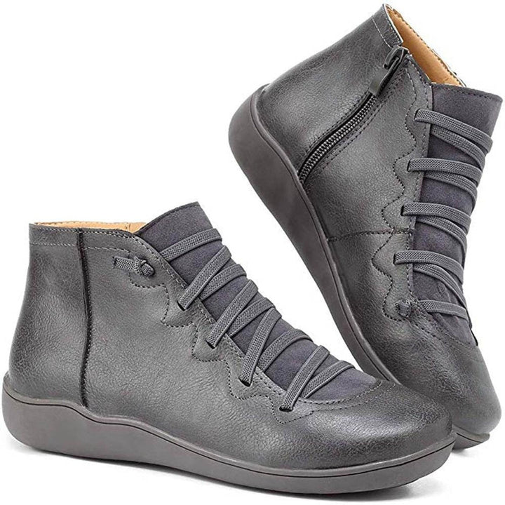 Close-up of women's flat ankle boots, highlighting the lace-up detail and functional side-zip.