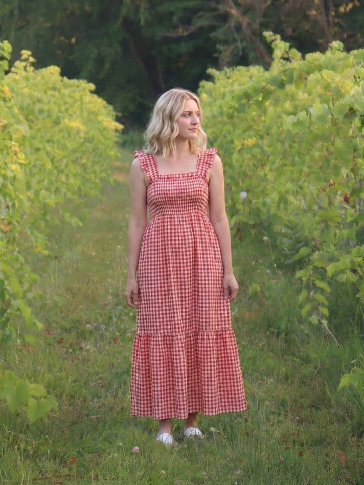Full-length view of a woman in a stylish flutter sleeve smocked gingham maxi dress, suitable for summer fashion.
