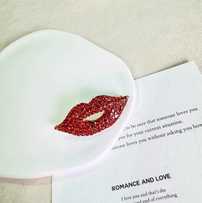 Close-up of a sparkling red lip brooch pin, a trendy women's accessory with shimmering glitter.