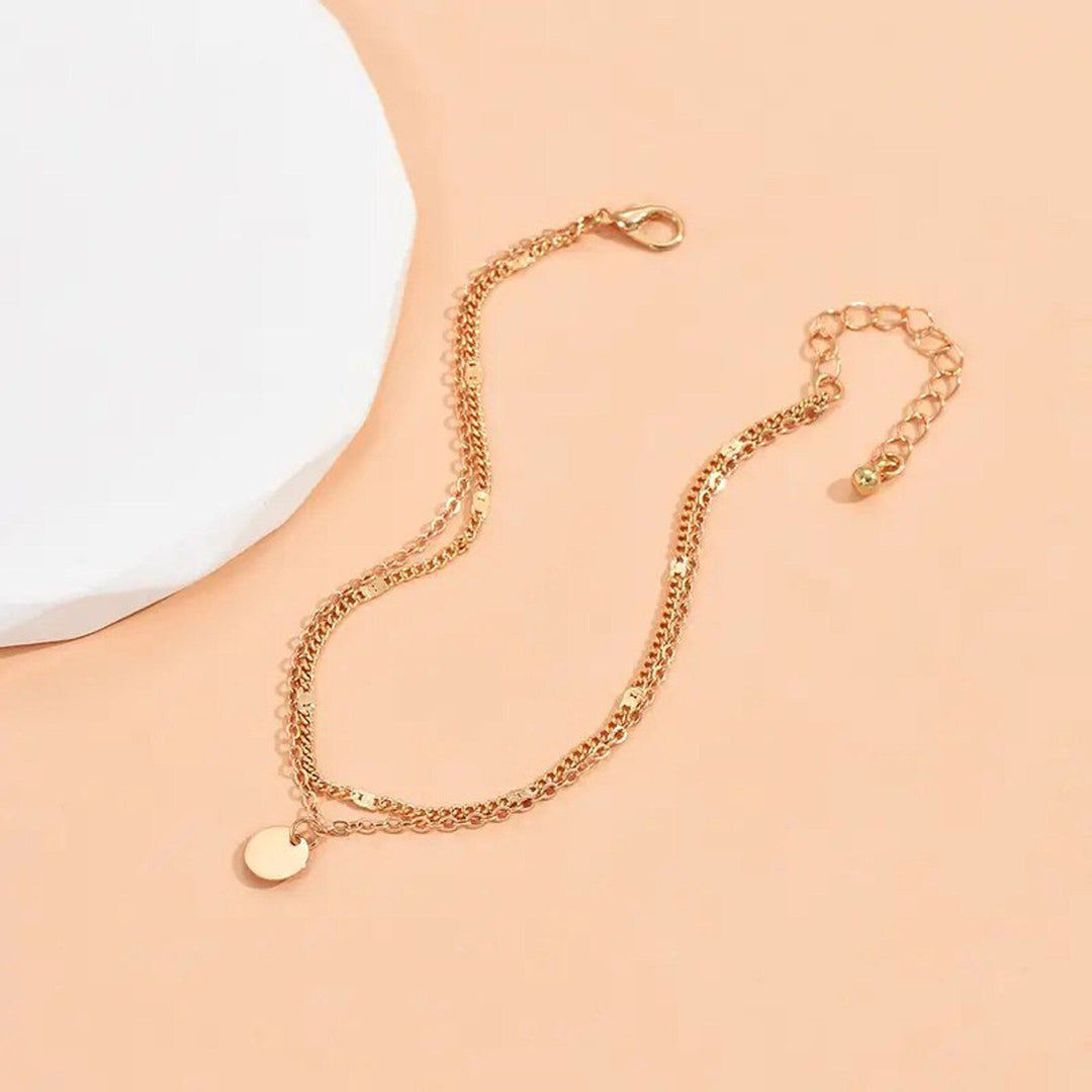 Chic gold layered charm anklet, a delicate and elegant statement piece for effortless summer style.