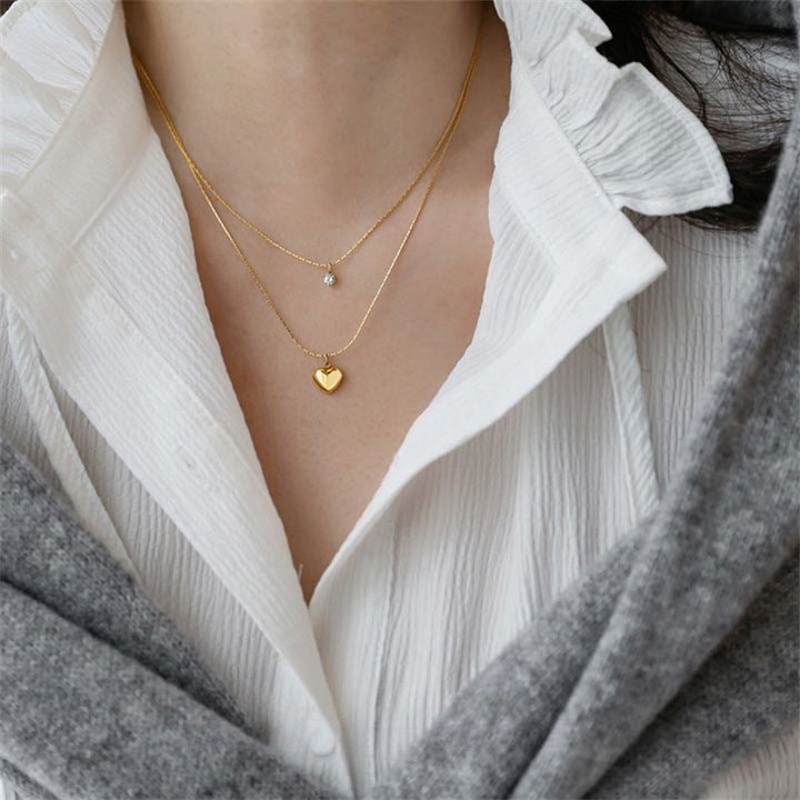 Delicate gold layered necklace for women, featuring a charming heart & a shimmering crystal pendant.