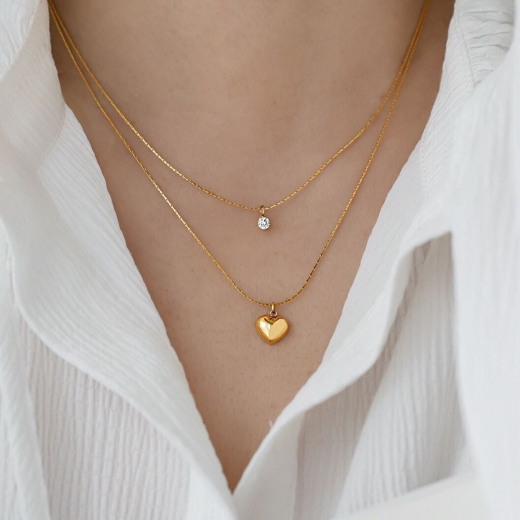 Women's elegant gold layered necklace featuring a cute heart charm and a dazzling crystal pendant.