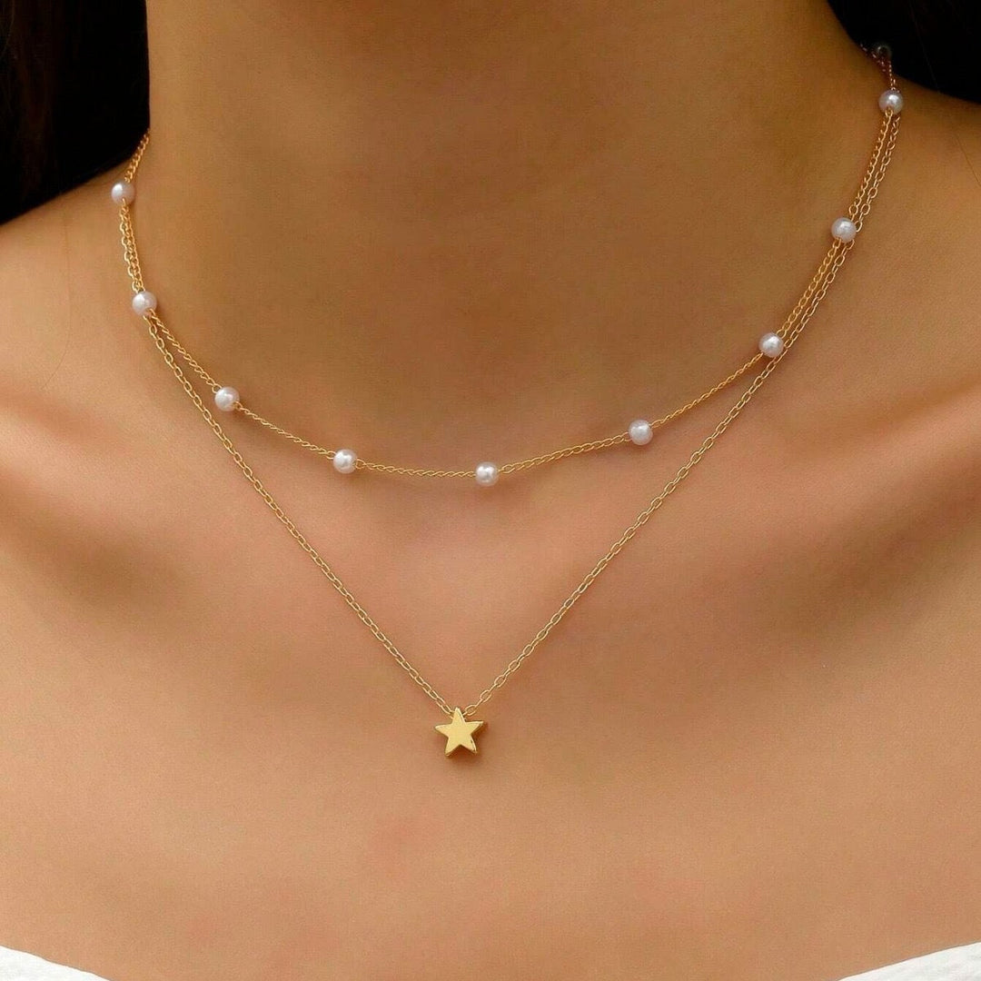 Women's gold-plated layered necklace with delicate pearl charms and sparkling star pendants, elegant fashion jewelry.