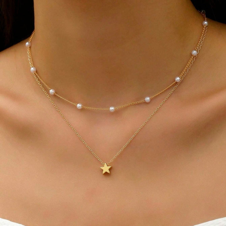 Women's gold-plated layered necklace with delicate pearl charms and sparkling star pendants, elegant fashion jewelry.