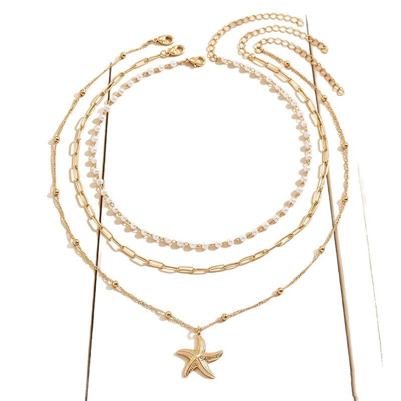Chic beach jewelry: layered gold plated necklace with a detailed starfish pendant & classic pearl. Summer essential.
