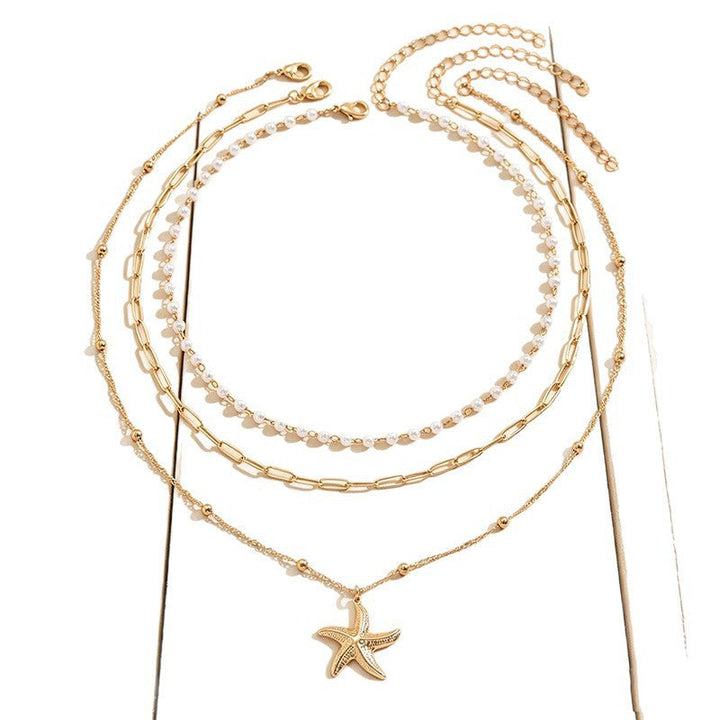 Chic beach jewelry: layered gold plated necklace with a detailed starfish pendant & classic pearl. Summer essential.