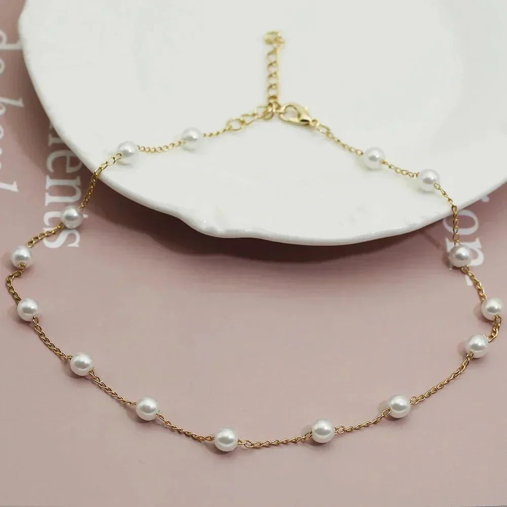Delicate women's gold choker necklace featuring small, evenly spaced pearls. A dainty and elegant fashion accessory.