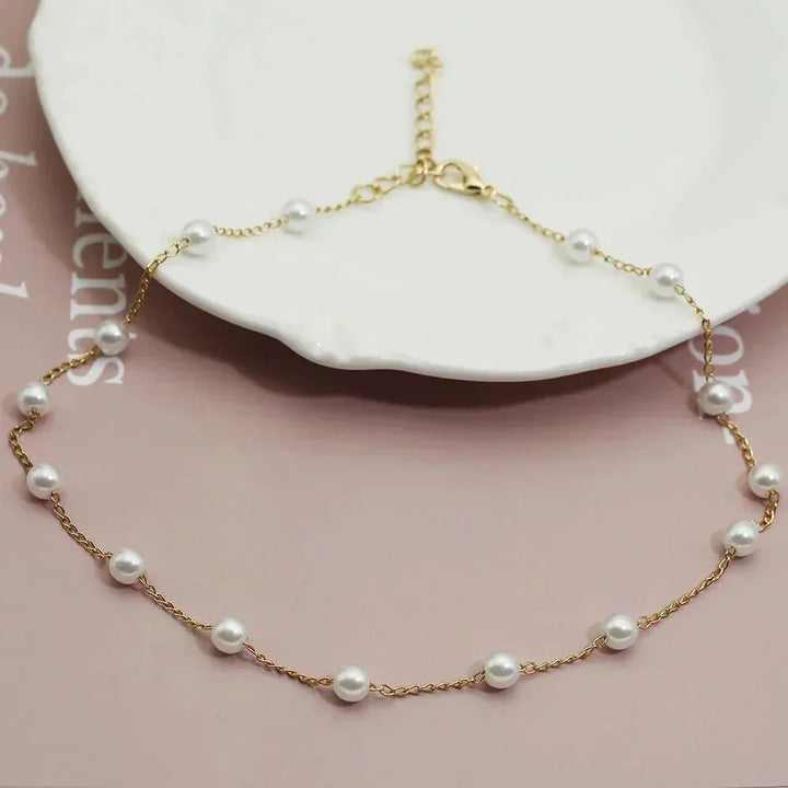 Delicate women's gold choker necklace featuring small, evenly spaced pearls. A dainty and elegant fashion accessory.